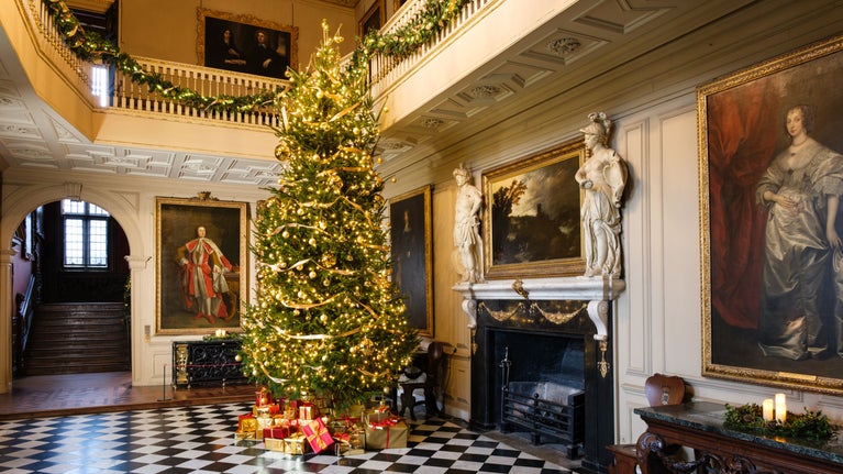 Christmas decorations including a large Christmas tree on the black and white tiled floor in the Great Hall at Ham House and Garden, Surrey